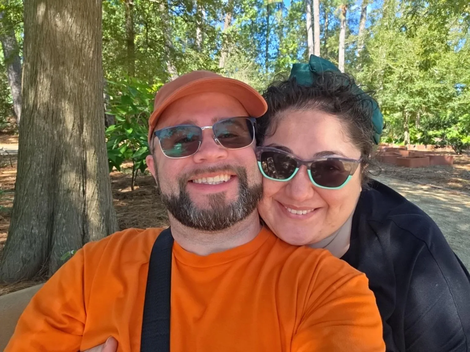 Efrain Ruiz in an orange cap and shirt with Kelly Trotman under trees