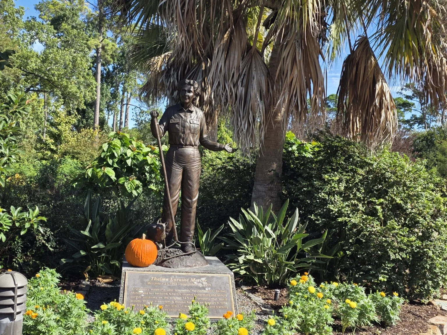 Statue with a plaque among plants and a pumpkin
