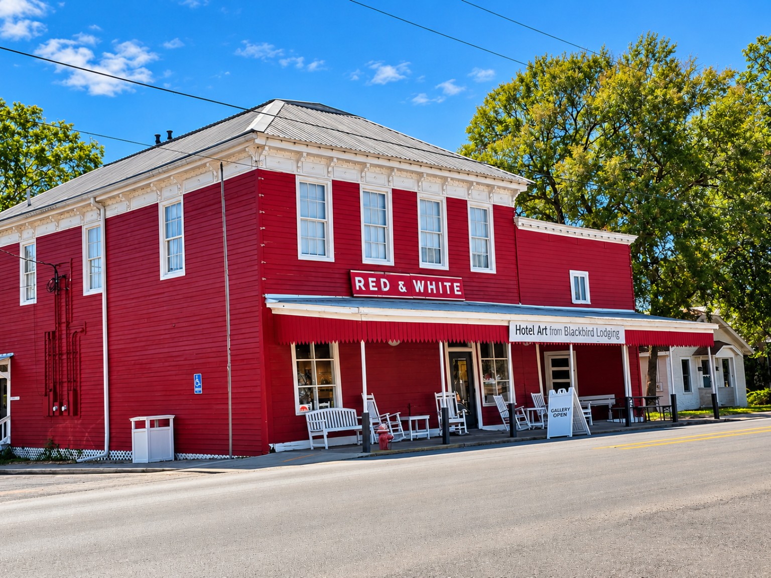Red and white two-story building with gallery sign and porch chairs