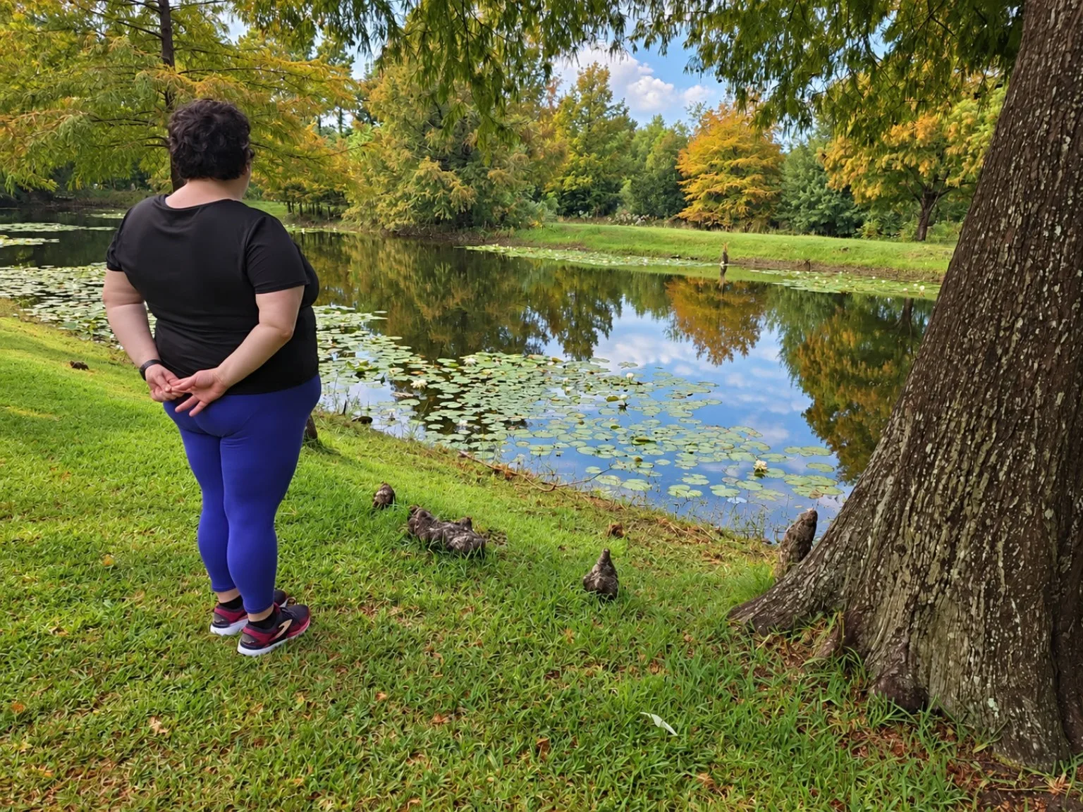 Kelly Trotman standing beside a leaf-covered pond