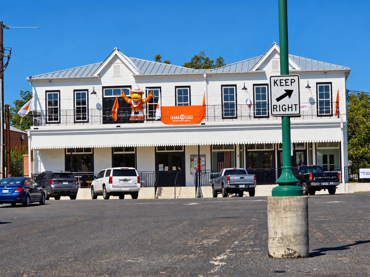 White two-story building in Fayetteville with a gray roof, porch and community bulletin board beside the entrance