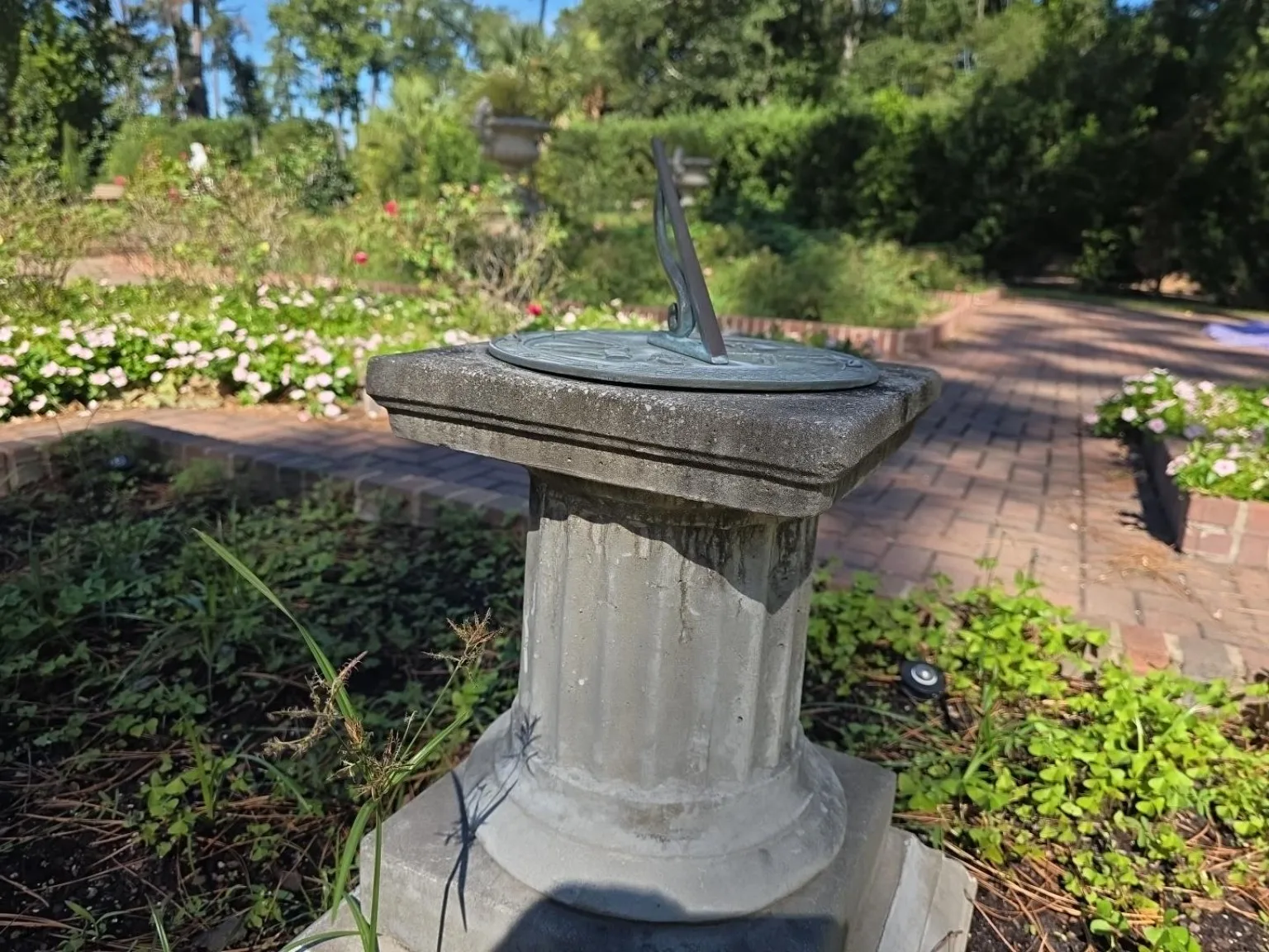 Sundial where brick paths meet, surrounded by flower beds