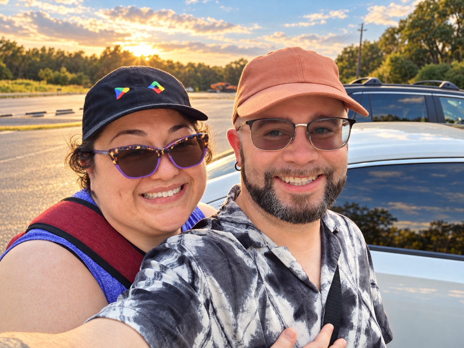 Kelly Trotman and Efrain Ruiz smiling together beside a car in warm sunset light.